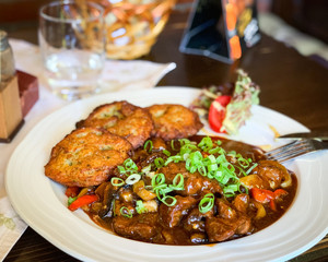 traditional czech goulash dish with fried potatoes & spring onion