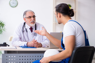 Fototapeta premium Young male contractor visiting old doctor