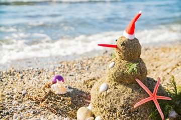 Snowman on holidays made of sand instead of snow. Concept tropical resort could be used for New...