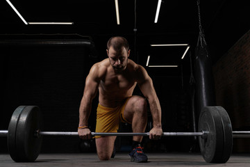 Fototapeta na wymiar Strong weightlifter with muscular body prepares to lift the barbell