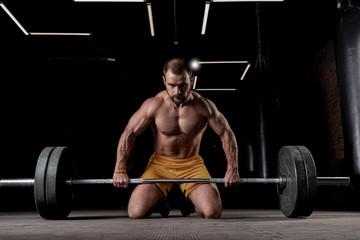Fototapeta na wymiar Strong weightlifter with muscular body prepares to lift the barbell