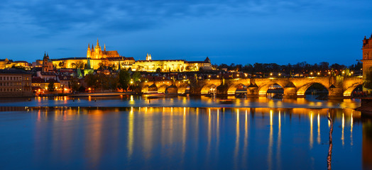 Prague skyline and bridge over river in night