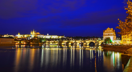 Prague skyline and bridge over river in night