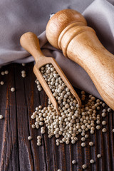 white peppercorns in wooden scoop on rustic background