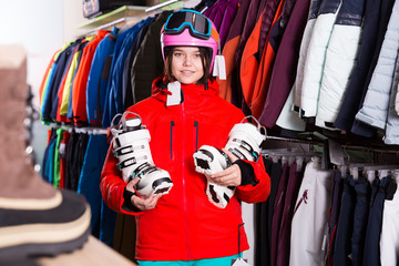 Fototapeta na wymiar Cheerful girl choosing ski boots for skiing