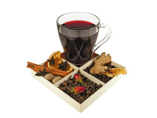 Mulled wine in glass cup with spices for making hot wine drink - dried orange slices, ginger, nutmeg, star anise, cinnamon sticks, cardamom, allspice, cloves and rose buds. Isolated on white.