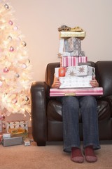 Person With Stack Of Christmas Gifts On Sofa
