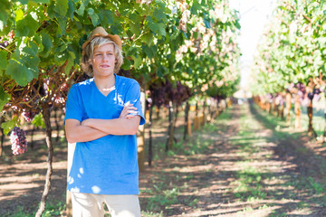 Guy standing with arms folded posing in vineyard