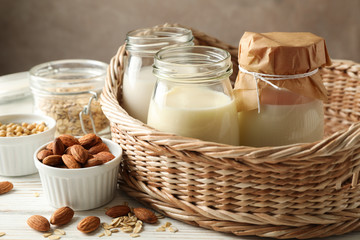 Basket with a glasses of different types milk on wooden background, space for text
