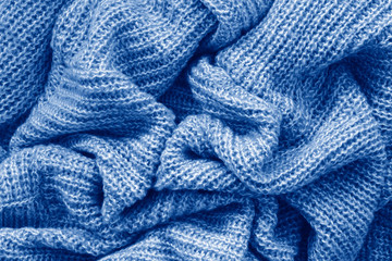Closeup classic blue texture of knitted wool material fabric or clothing. Toned trendy 2020 year colour background with wrinkles and folds. Dark blue monochrome backdrop wallpaper.