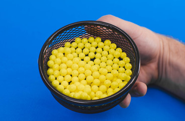 a man's hand holds in a basket a bunch of yellow pills on a blue background. the concept of health.