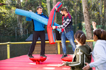 Men having funny wrestling by inflatable logs