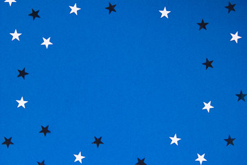 Frame with confetty stars sequins on Classic blue background. Colour trend 2020. Top view. Copy space for text. Concept of winter holiday.
