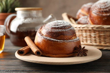Cinnamon rolls, tea and plant on wooden table, closeup