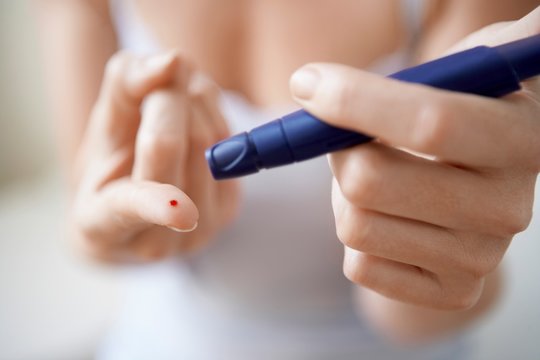 Woman Using Lancelet On Finger