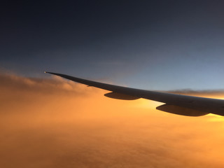 Wing of airplane flying above the clouds