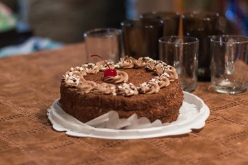 dark cake with cherry on the background of empty glass glasses