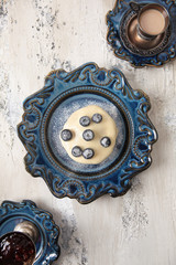 Pancake or dessert with vanilla sauce and blueberries on a blue ceramic plate. The view from the top. Copy space.