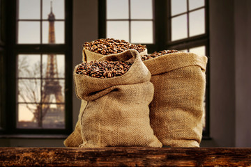 Fresh coffee beans in sacks on wooden old table and free space for your decoration.Wooden background with city landscape and morning time. Copy space. 