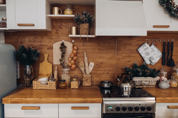Close-up of modern cozy kitchen in white and brown colors with stuff, cooker and decorative fir...