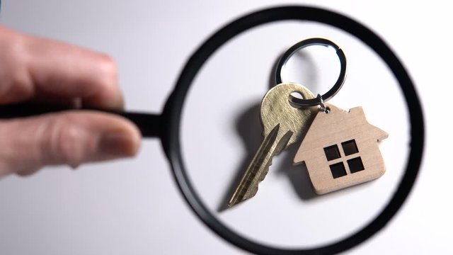 Person examining home key through loupe, quality of housing service, cooperative