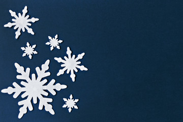 White felt snowflakes on a dark blue background. New Year card.