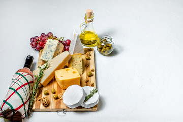 Obraz na płótnie Canvas Different sorts of cheese. Cheese platter with different cheese, bottle of wine, nuts and spices on white background. Top view, wiht copy space