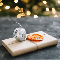 Christmas craft paper gift decorated with  dried orange slices near Christmas tree. New Year decoration concept.  flat lay