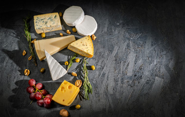 Different sorts of cheese. Cheese platter with different cheese, and spices on dark background. Top view, wiht copy space