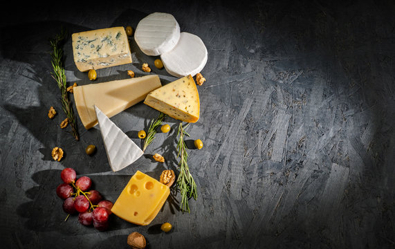 Different sorts of cheese. Cheese platter with different cheese, and spices on dark background. Top view, wiht copy space