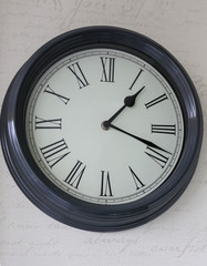 Round wall clock with Roman numerals hanging on the wall