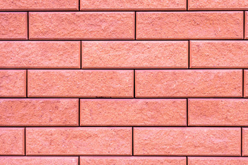Creative pink background. Brick texture of unusual coral color.