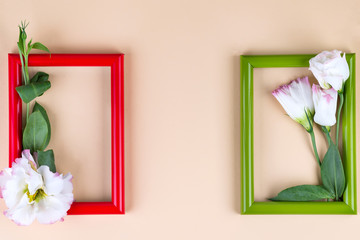 Empty frame and flowers flat lay on beige paper background with copy space. Holiday concept