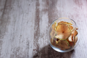 Tasty chips of green apples in a glass bowl on a wooden table. Place for text. Copy space.