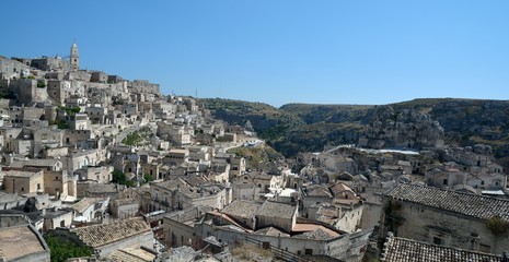 Obraz premium Matera is a city located on a rocky outcrop in Basilicata, in Southern Italy. It includes the area of the Sassi, a complex of Cave Houses excavated in the mountain.
