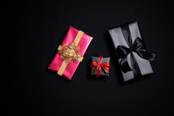 Top view of black gift box with red and black ribbons isolated on black background.