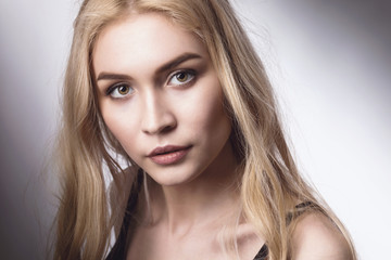 Naklejka premium Portrait of a young beautiful blonde girl looking at the camera