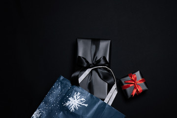 Top view of black gift box with red and black ribbons isolated on black background.