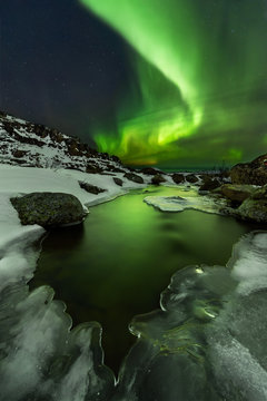 Northern lights under Barents sea. Polar landscape at the winter night.