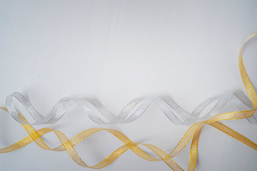 Shiny gold and silver ribbons lie on a white background. Frame of ribbons. Festive background. Flat lay, top view, copy space