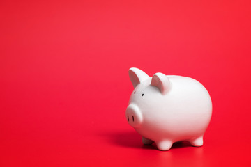 Composition with piggy bank isolated on red background.