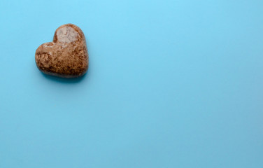 Valentine's flat lay with love chocolate gingerbread heart on colorful blue background, greeting card copy space top view. The celebration of Valentine's Day.