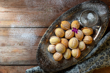 Homemade cookies in the form of nuts filled with sweet condensed milk on an old wooden background. Homemade Russian cookies.