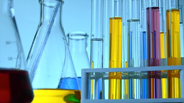 flasks and test tubes stand in a laboratory with colored chemical liquids