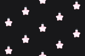 Pink star shaped Cristmas tree baubl ornaments  arranged in a row on dark black flat lay background