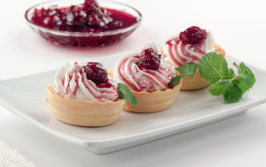 Homemade tartlets with cream cheese, cherry jam and mint