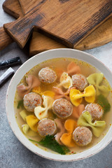 Close-up of meatball soup with farfalle pasta, vertical shot, elevated view