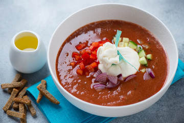 Tomato gazpacho with burrata cheese, chopped bell pepper, red onion, cucumber and olive oil served in a white bowl