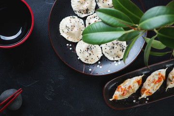 Pan fried potstickers and steamed asian dumplings over black stone background, horizontal shot with space, top view