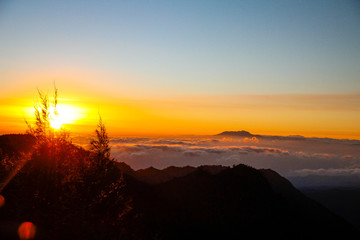 The sun rises above the clouds to the left of the Bromo volcano on the island of Java. Indonesia